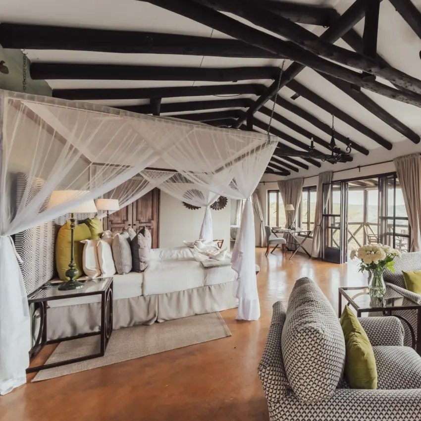 Luxury bedroom suite with canopied bed and exposed beam ceiling overlooking savanna, The Emakoko, Nairobi, Kenya