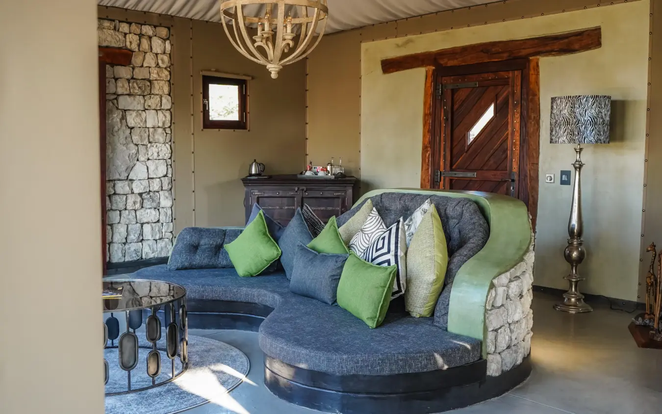 Modern lounge with curved seating and stone fireplace, Etosha Oberland Lodge, Etosha National Park, Namibia