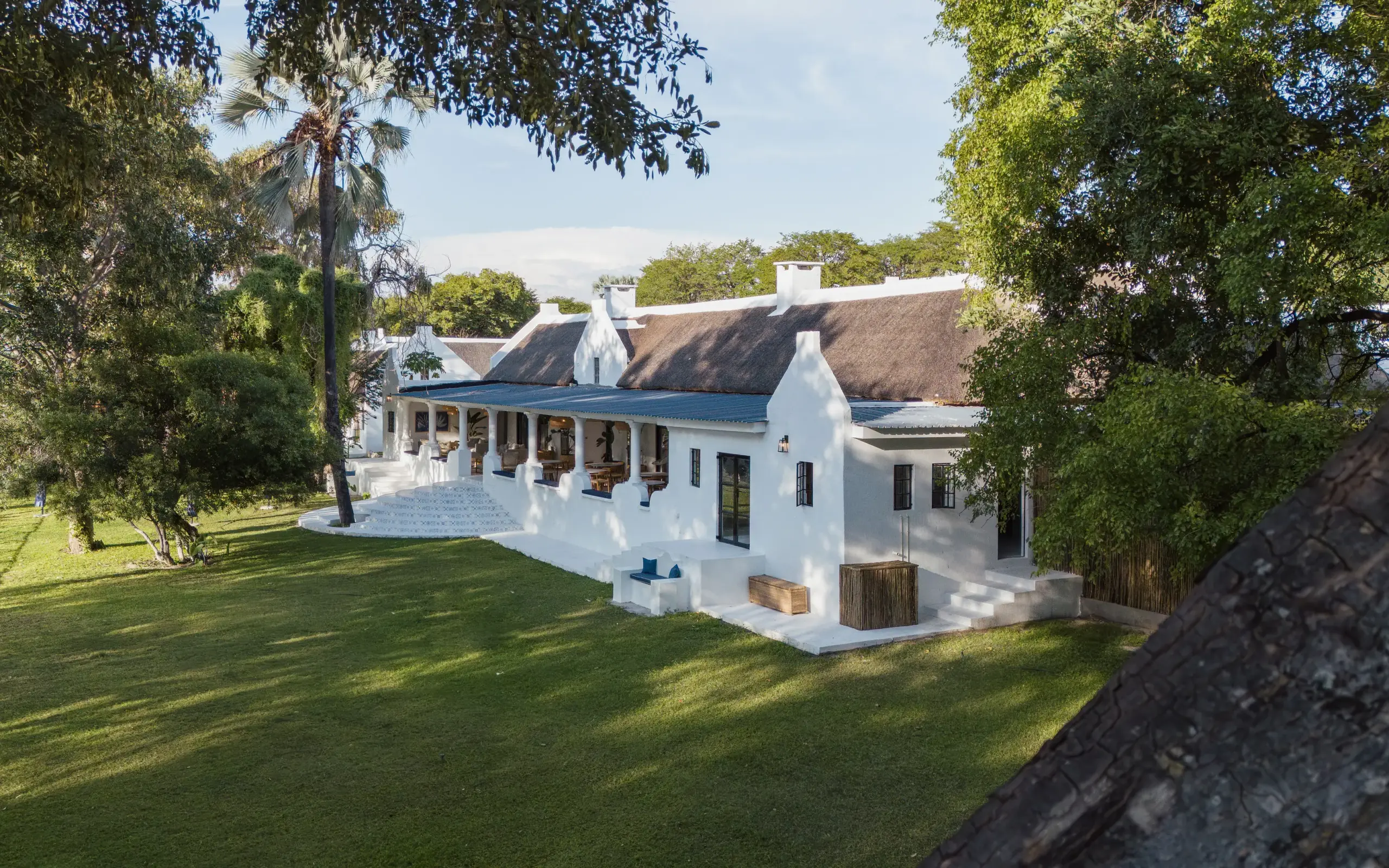 White colonial-style lodge with thatched roof and manicured gardens, Botswana