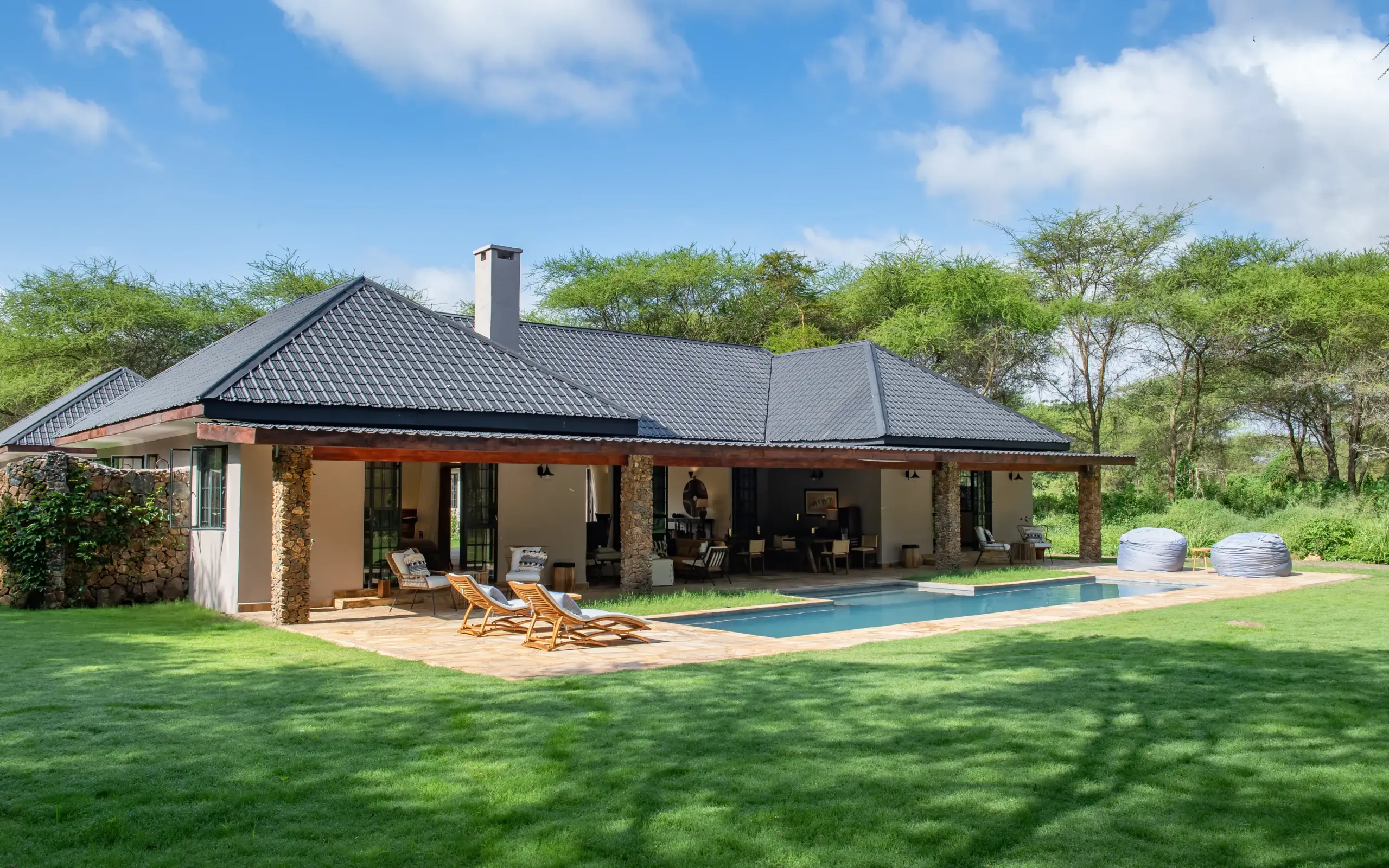 Modern safari lodge with pool overlooking expansive manicured gardens and acacia trees, Hamerkop House, Arusha, Tanzania