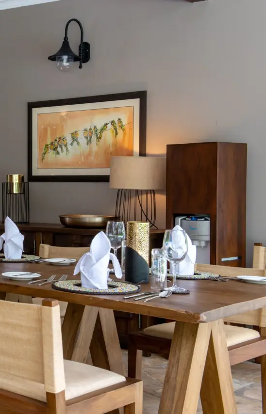 Fine dining room with wooden table and contemporary artwork on wall, Hamerkop House, Arusha, Tanzania