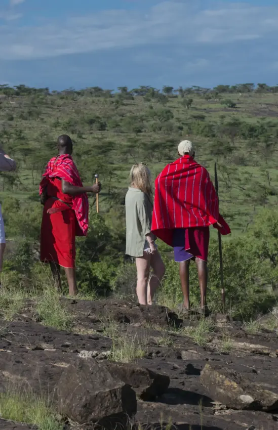 Maasai guides and tourist on overlook of acacia woodland savanna, Hemingways River Camp Mara, Maasai Mara, Kenya