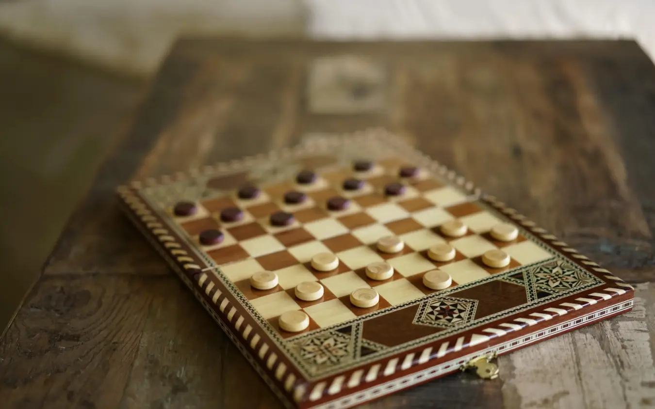 Wooden checkers game board with carved pieces on decorative inlaid table, Hemingways River Camp Mara, Maasai Mara, Kenya