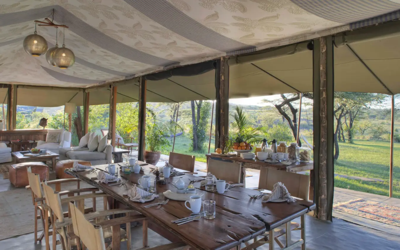 Open-sided dining tent with table settings overlooking savanna landscape, Hemingways River Camp Mara, Maasai Mara, Kenya