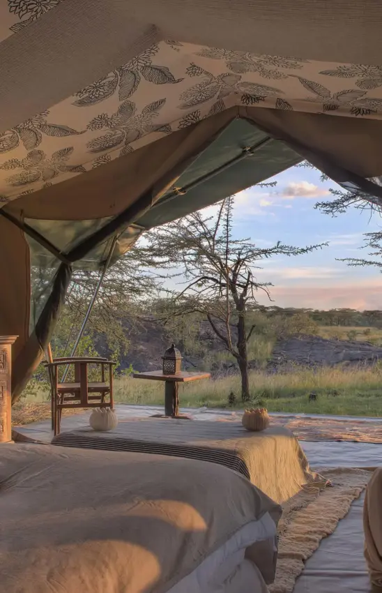 Luxury tent interior with view of savanna landscape at dusk, Hemingways River Camp Mara, Maasai Mara, Kenya
