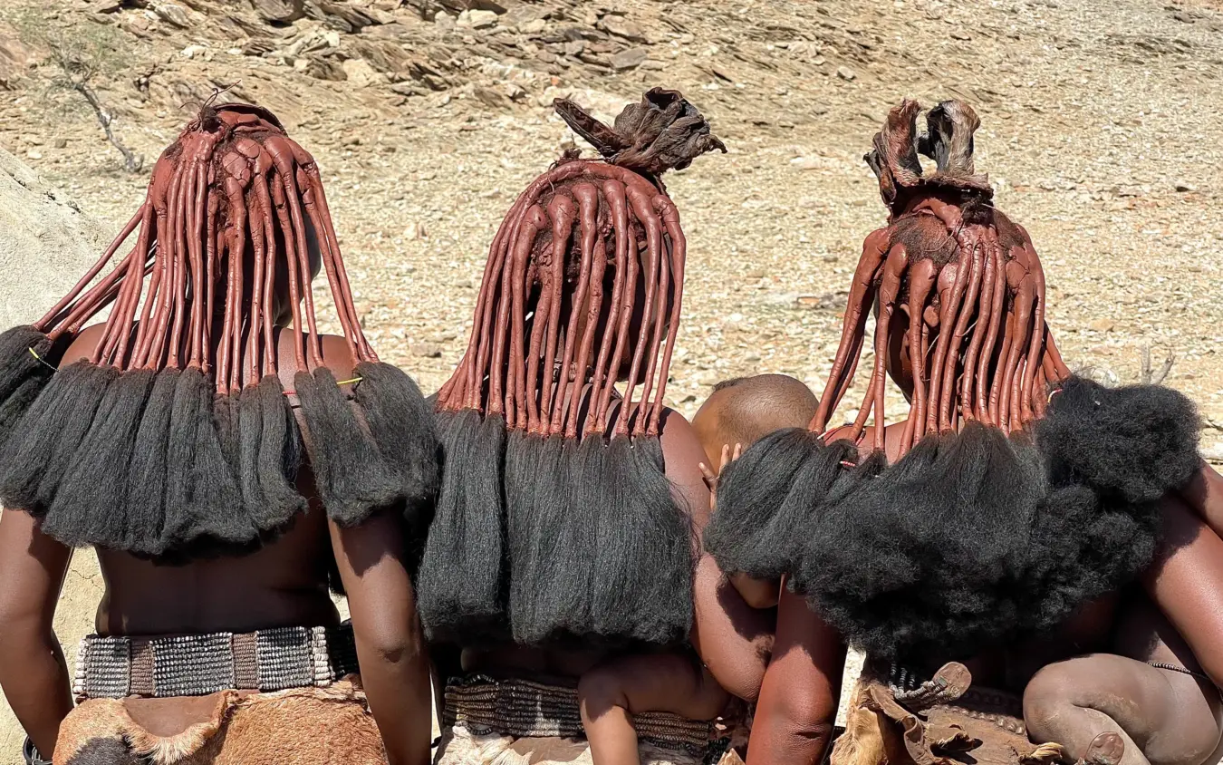 Three people with distinctive red braided hair viewed from behind, Hoanib Valley Camp, Damaraland, Namibia