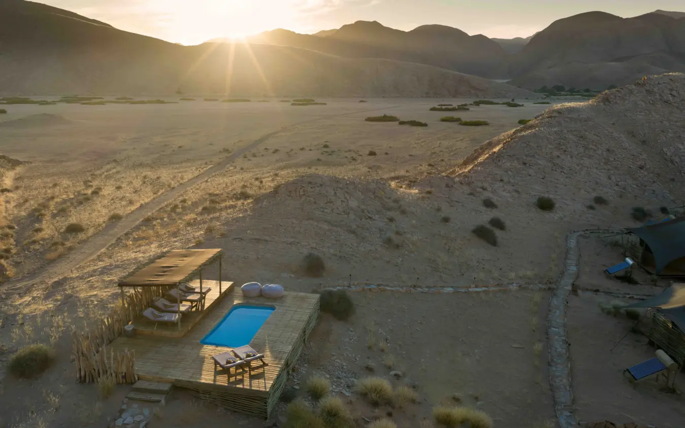 Luxury lodge with pool overlooking desert lake at sunset, Hoanib Valley Camp, Damaraland, Namibia