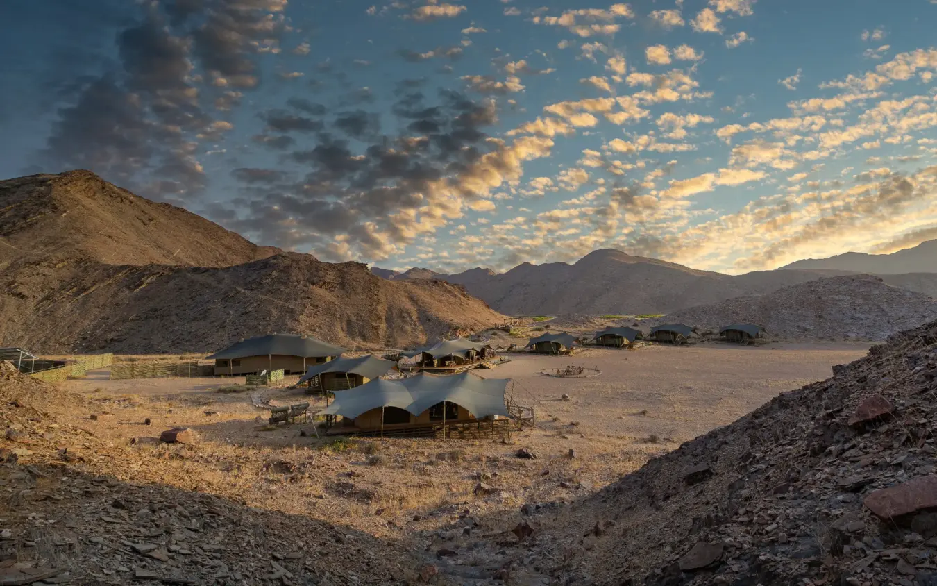 Luxury safari camp with canvas tents in desert valley at sunset, Hoanib Valley Camp, Damaraland, Namibia