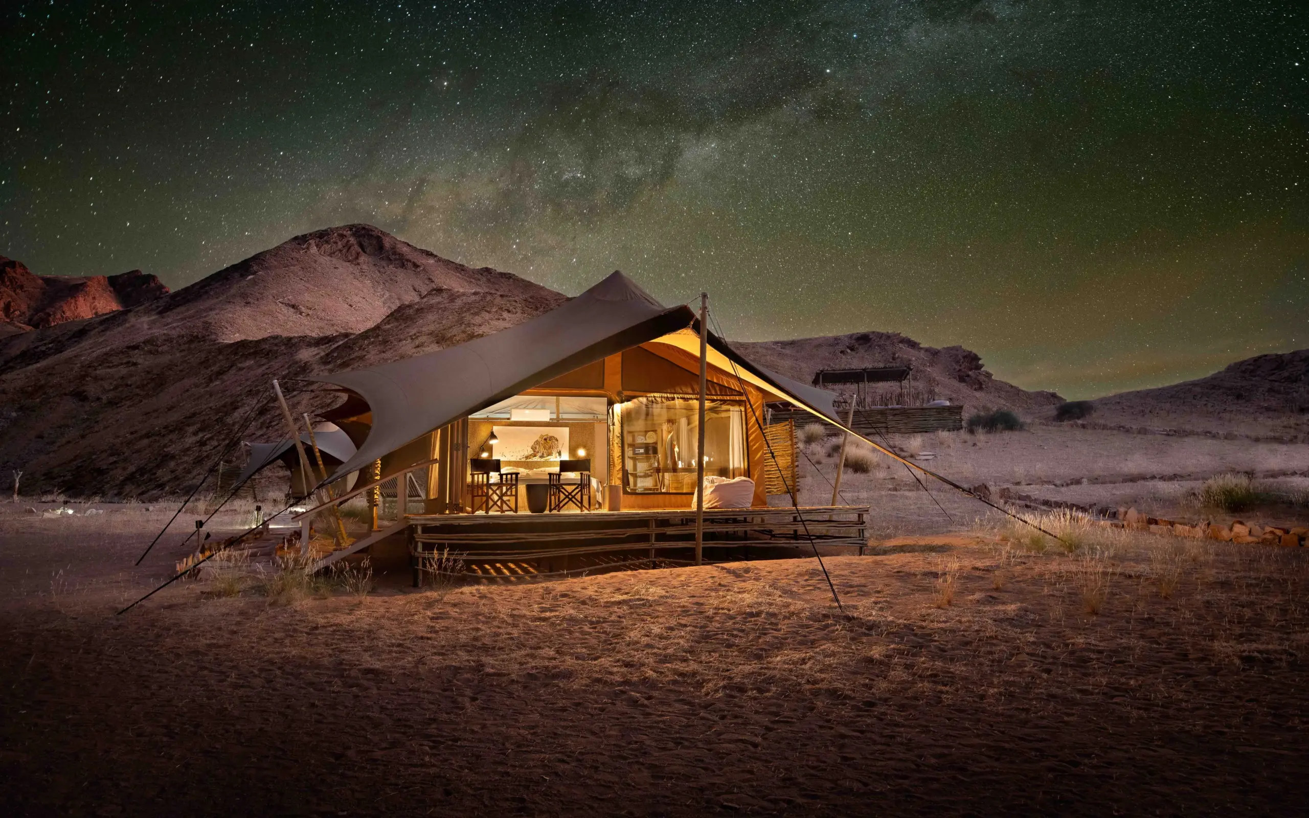 Illuminated canvas safari tent under starry night sky in desert landscape, Hoanib Valley Camp, Damaraland, Namibia