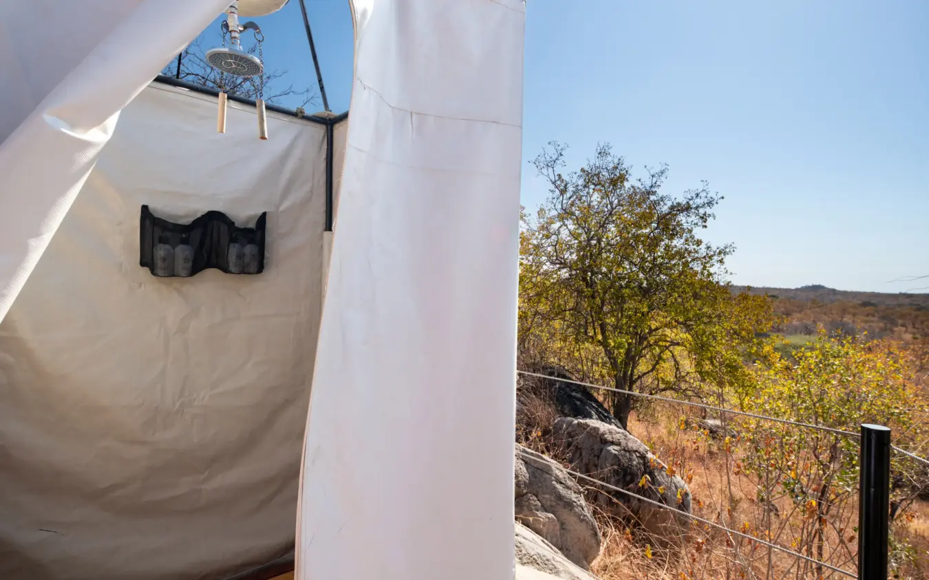 Outdoor shower tent with valley landscape view during daytime, Ikuka Safari Camp, Ruaha National Park, Tanzania