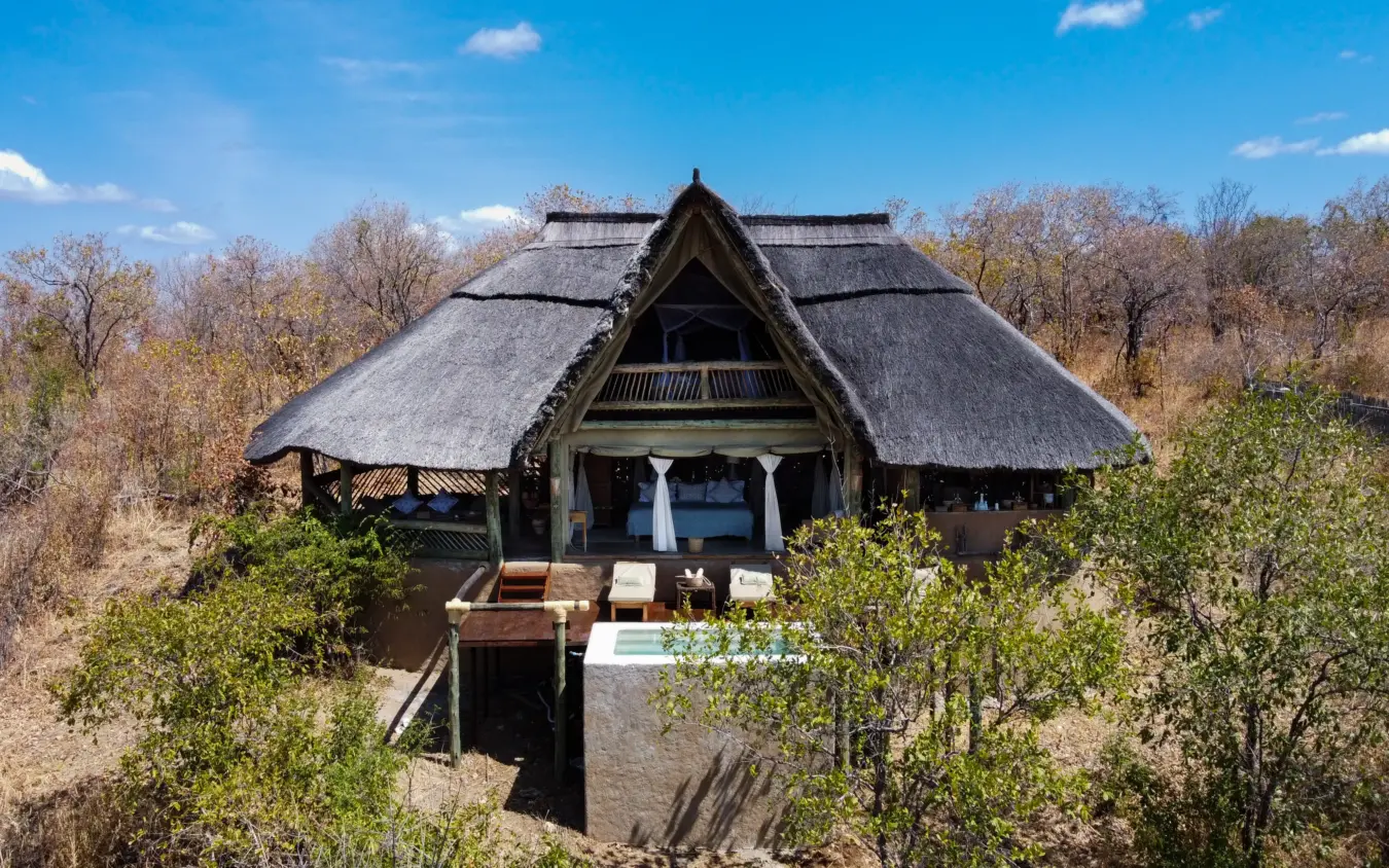 Thatched-roof lodge with wooden deck overlooking bushland landscape, Ikuka Safari Camp, Ruaha National Park, Tanzania