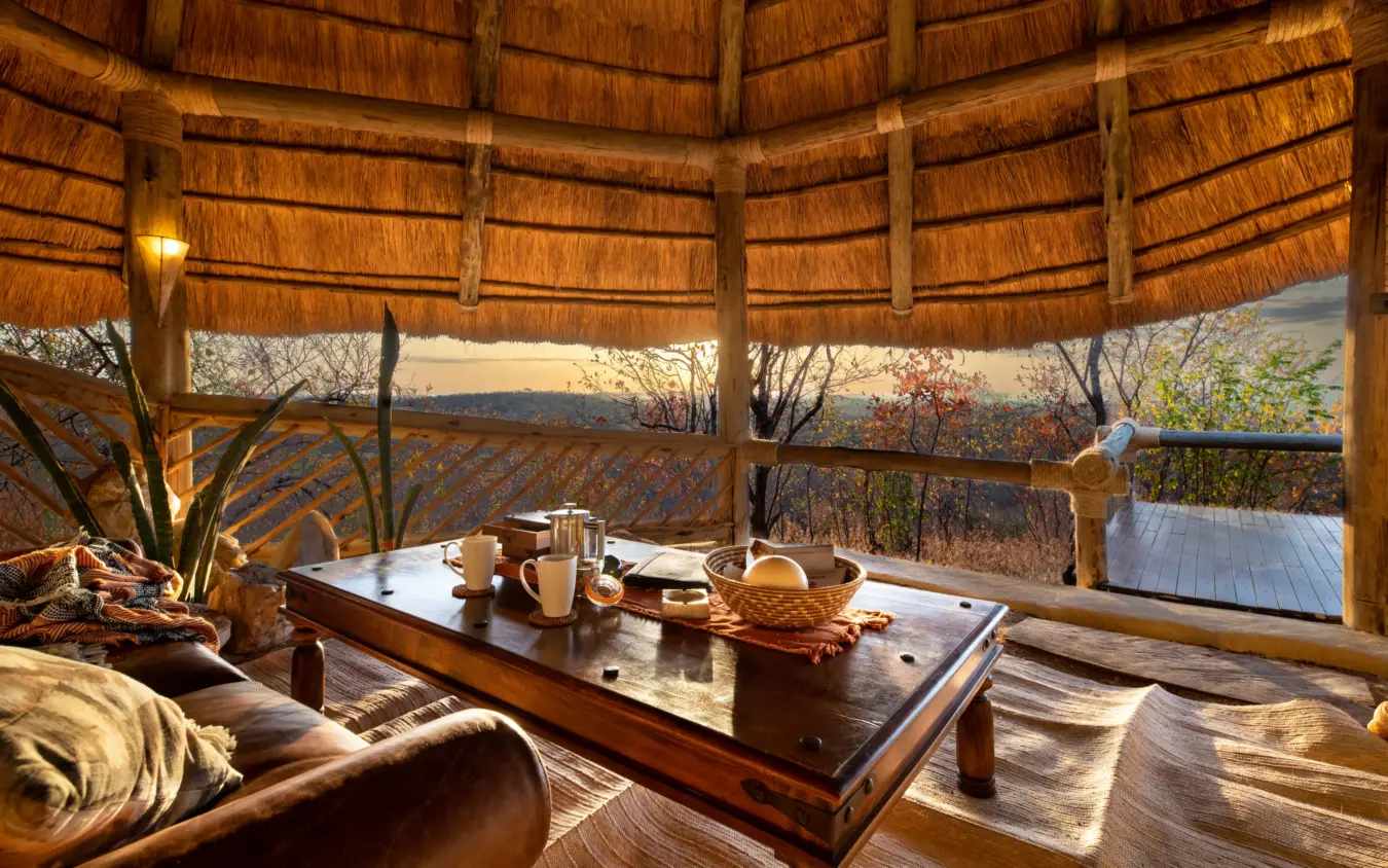Thatched safari lodge interior with valley views at sunset, Ikuka Safari Camp, Ruaha National Park, Tanzania