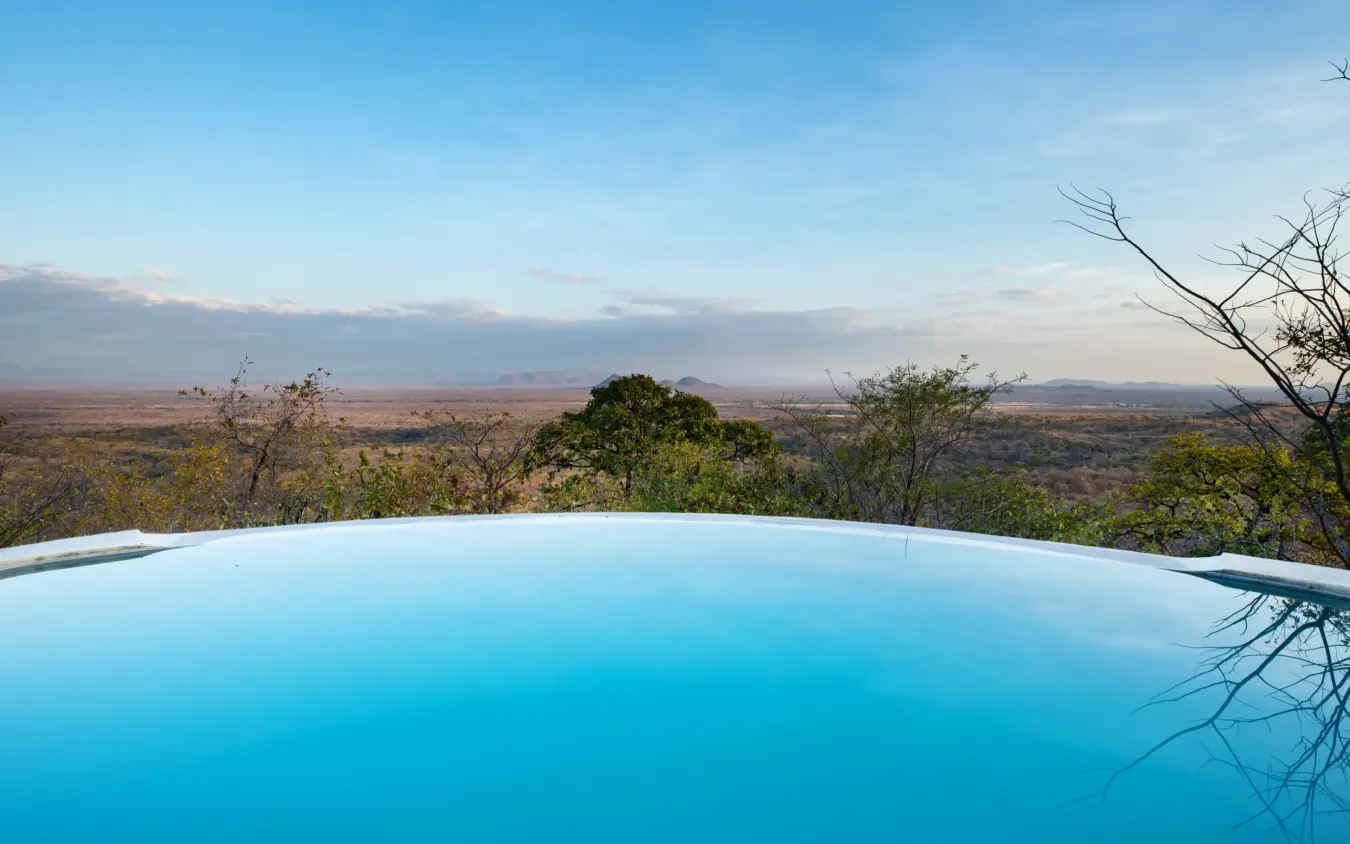 Infinity pool overlooking savanna landscape at dusk, Ikuka Safari Camp, Ruaha National Park, Tanzania