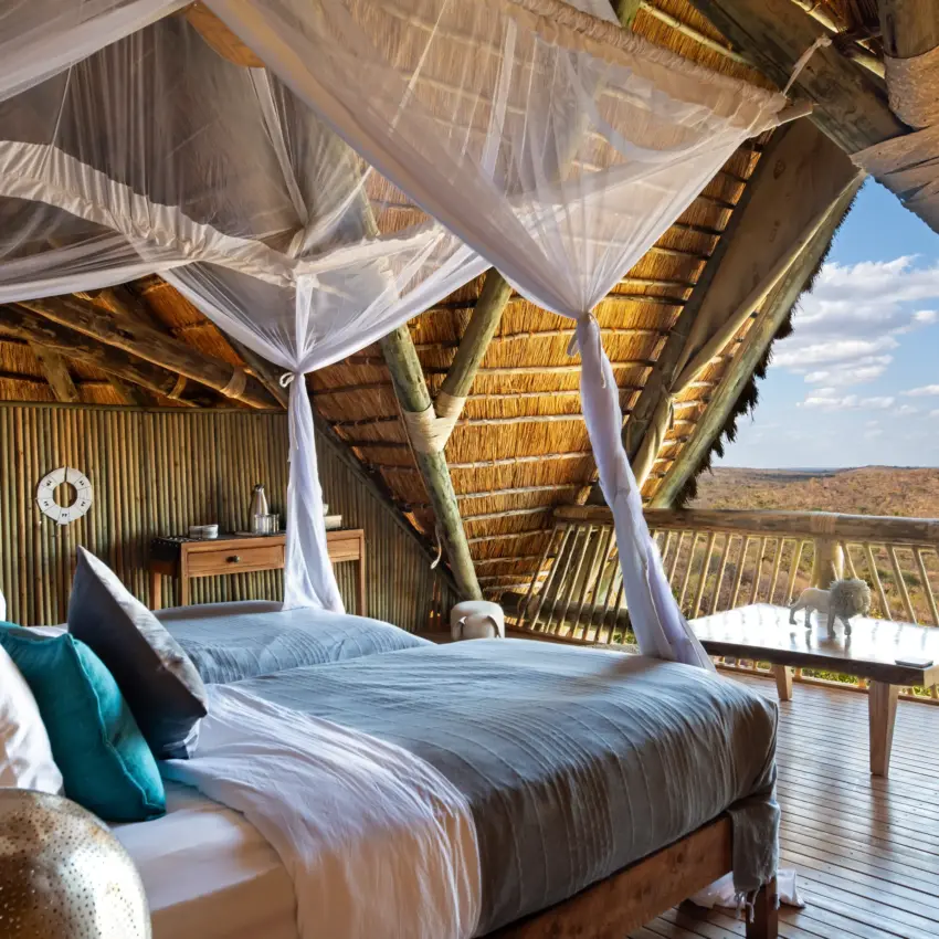Canopy bedroom with sheer curtains and savanna views from wooden deck, Ikuka Safari Camp, Ruaha National Park, Tanzania