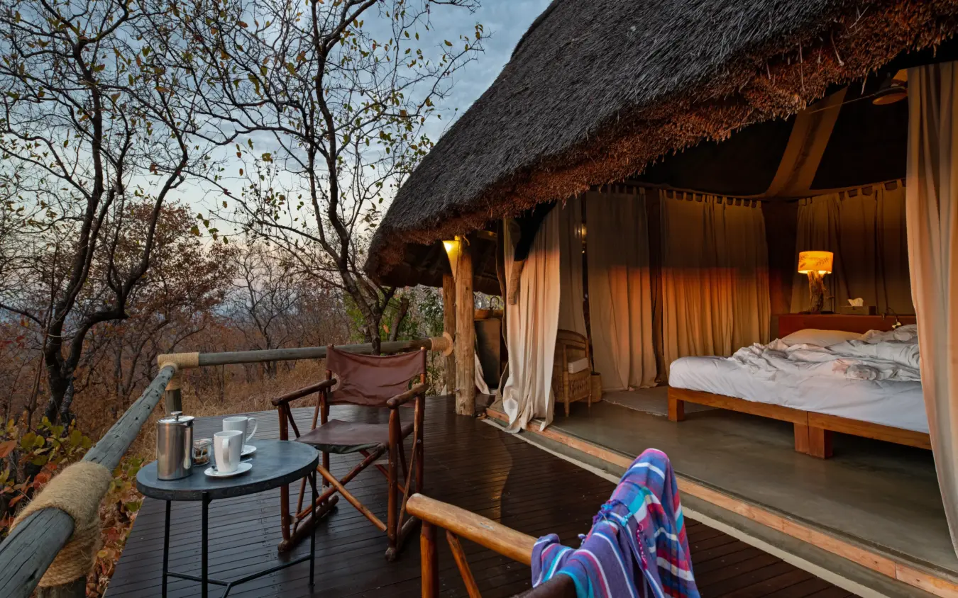 Guest's feet in colorful socks relaxing on luxury safari lodge deck at sunset, Ikuka Safari Camp, Ruaha National Park, Tanzania