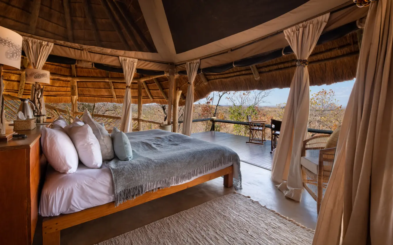 Luxury bedroom pavilion with thatch roof overlooking savanna landscape, Ikuka Safari Camp, Ruaha National Park, Tanzania