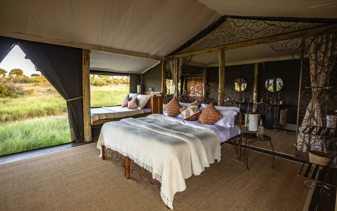 Luxury safari tent bedroom with views across grassland savanna, Kimya Kimya Camp, Maasai Mara, Kenya