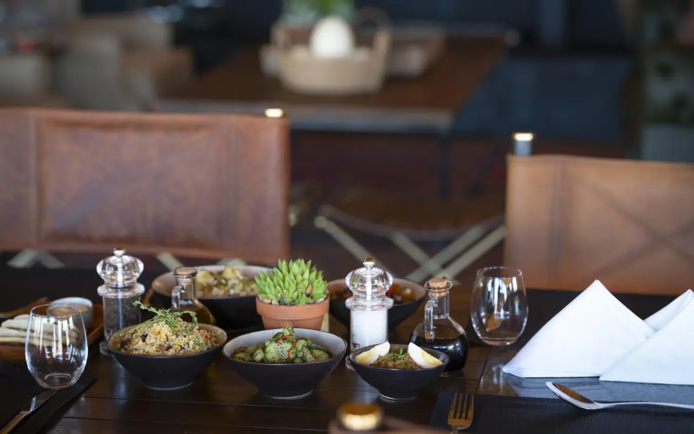 Restaurant table set with small plates of food and succulent plant centerpiece, Kwessi Dunes, NamibRand Private Reserve, Namibia