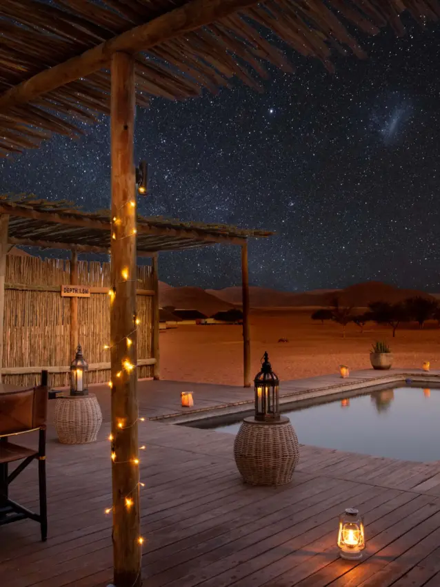 Desert pool deck with starlit sky and wooden pergola at night, Kwessi Dunes, NamibRand Private Reserve, Namibia