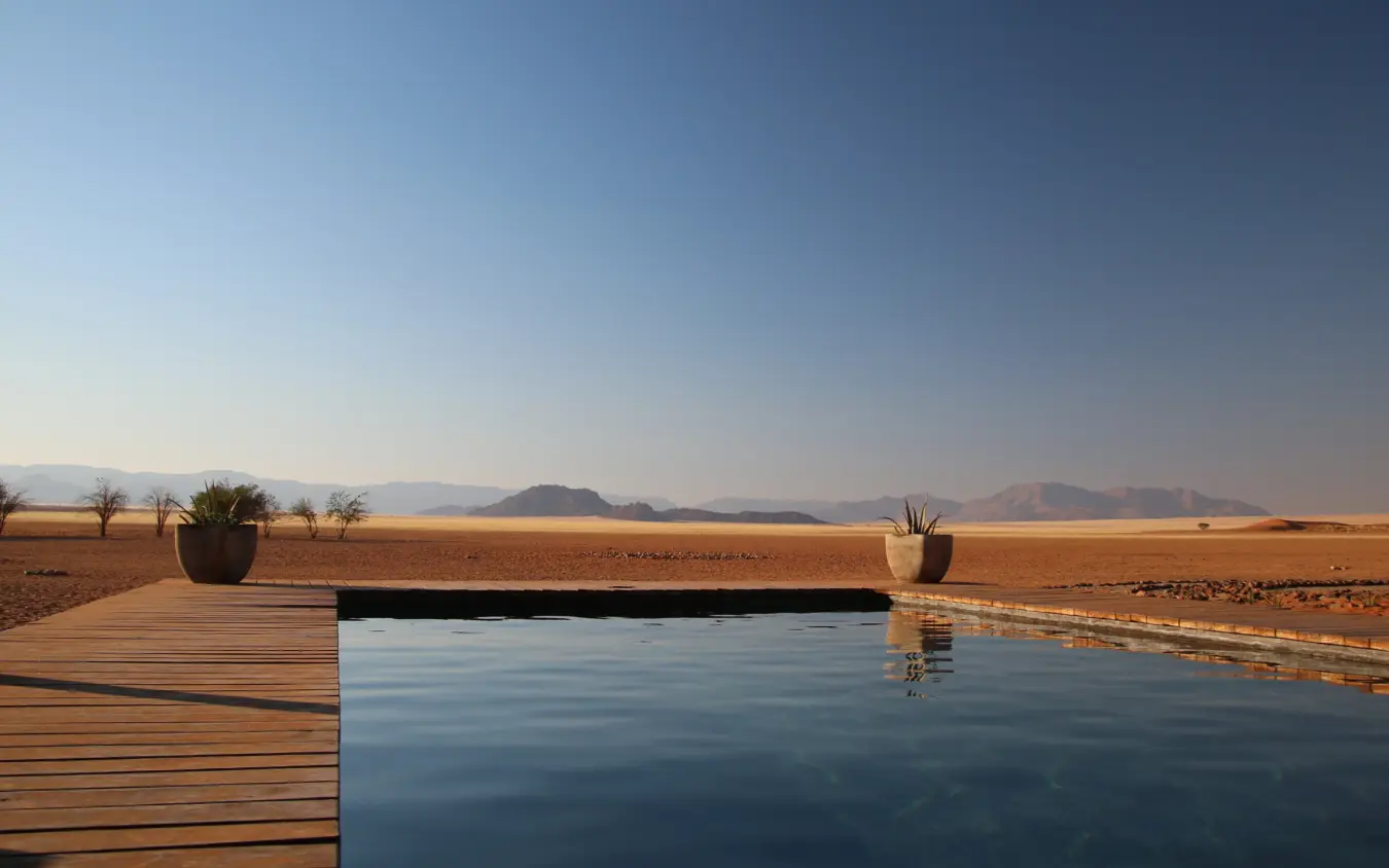 Infinity pool overlooking desert landscape with distant mountains, Kwessi Dunes, NamibRand Private Reserve, Namibia