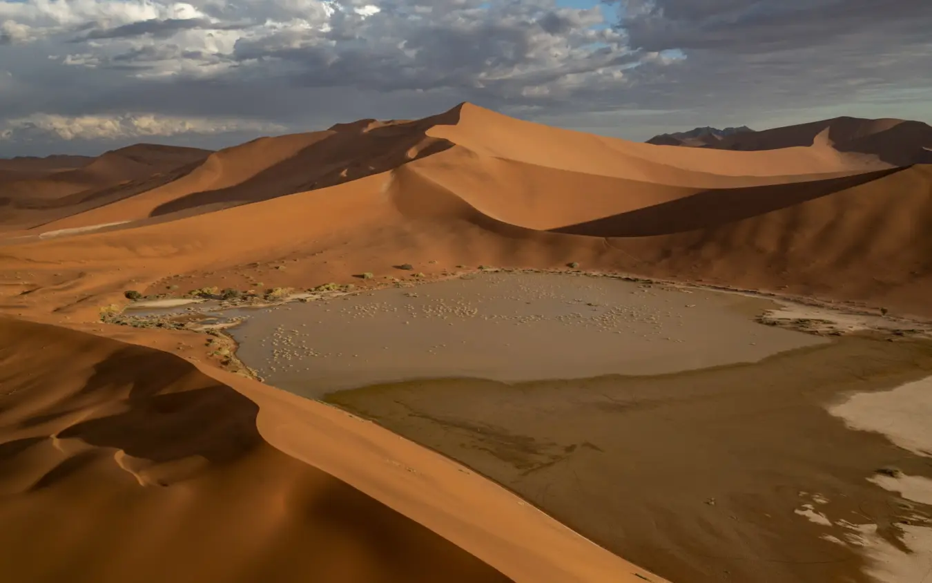 Sand dunes surrounding a saltwater lake in arid desert landscape, Kwessi Dunes, NamibRand Private Reserve, Namibia