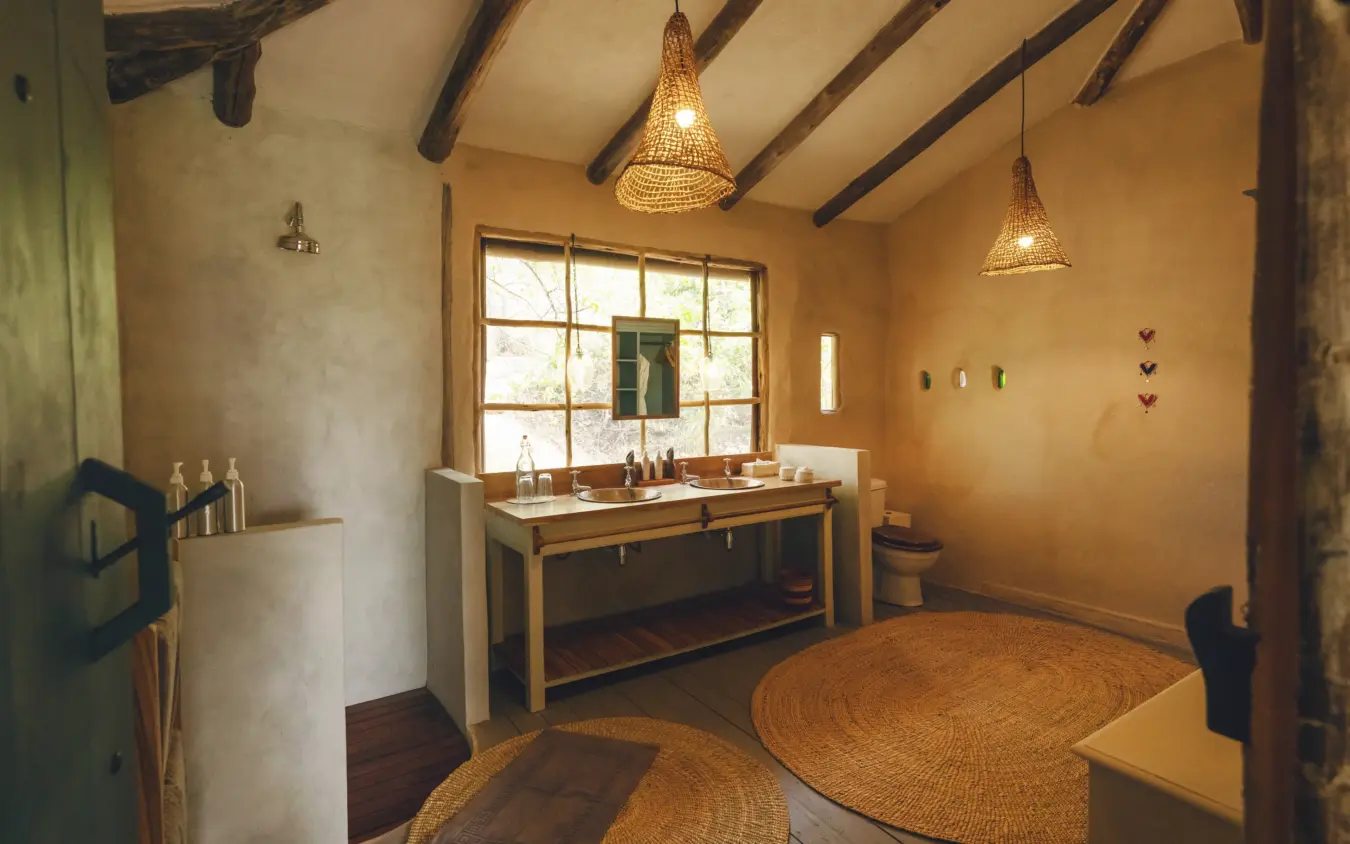 Luxury bathroom with wooden vanity and woven pendant lights under exposed beams, Lamai Serengeti, Serengeti National Park, Tanzania