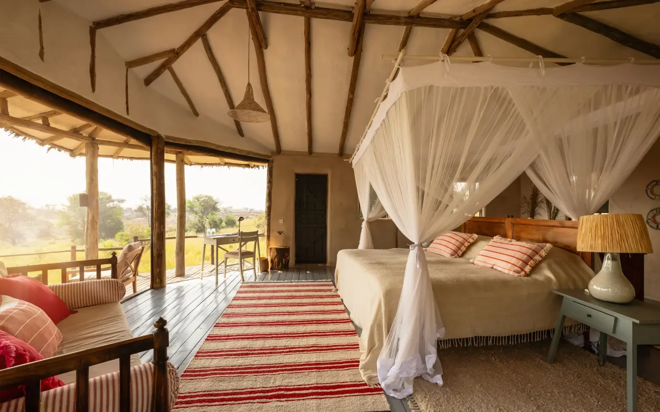 Luxury bedroom with four-poster bed and open veranda overlooking savanna landscape, Lamai Serengeti, Serengeti National Park, Tanzania