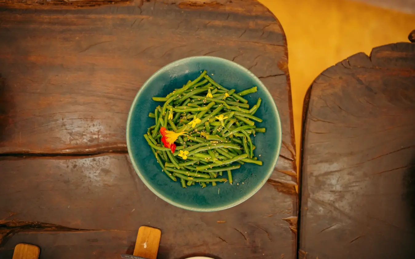 Green bean dish with chili garnish on rustic wooden table, Lewa House, Laikipia Highlands, Kenya