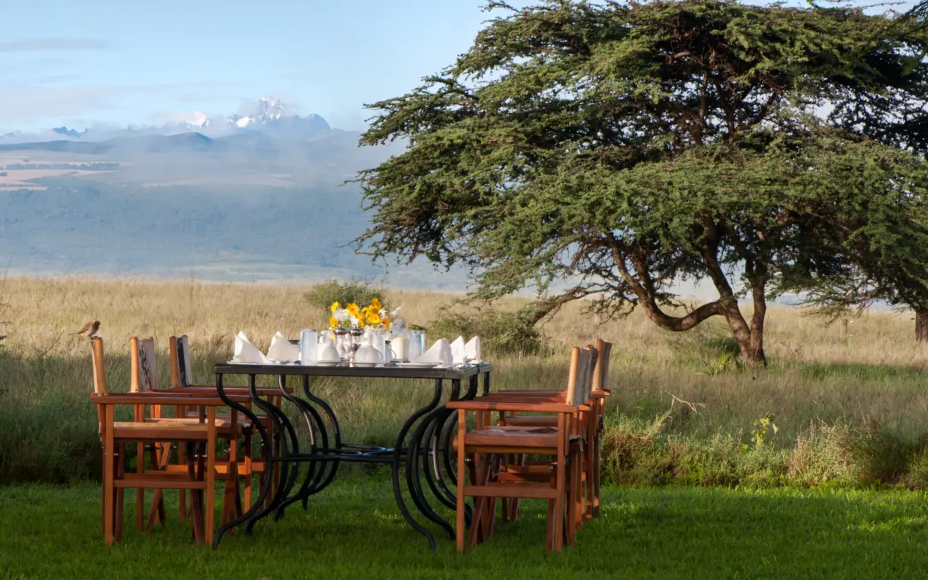 Outdoor dining setup with mountain views across savanna landscape, Lewa House, Laikipia Highlands, Kenya