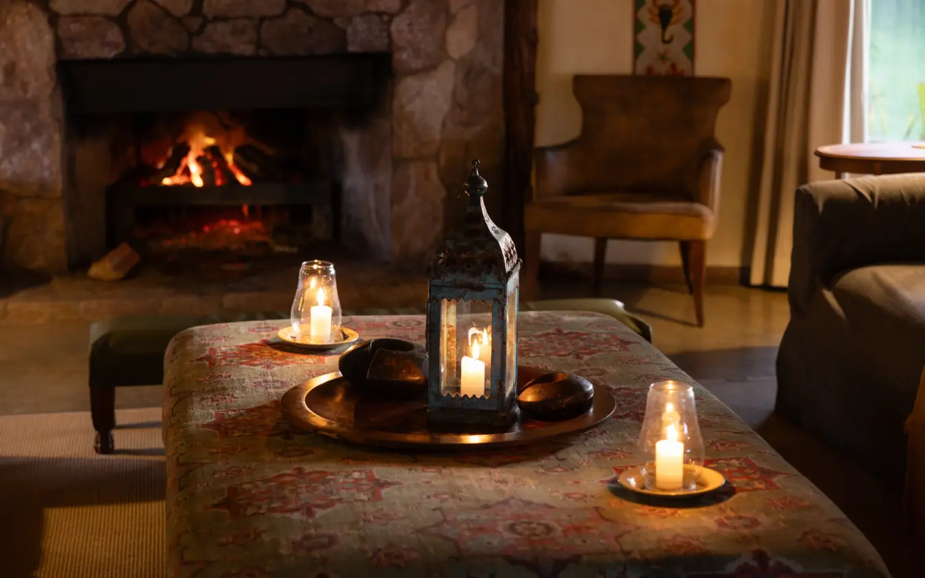 Fireplace lounge with candlelit table and leather seating, Lewa House, Laikipia Highlands, Kenya