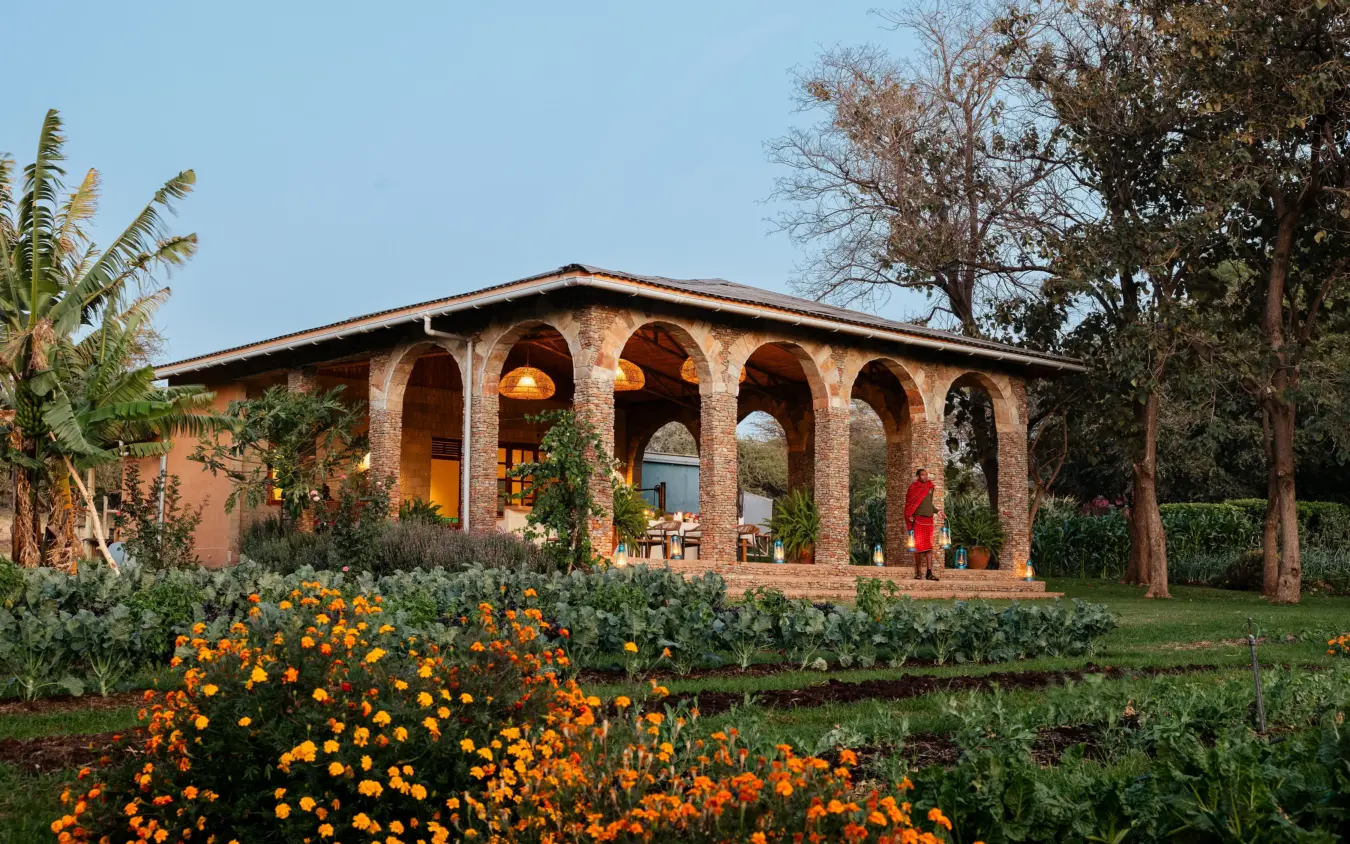 Terracotta villa with arched colonnade and manicured gardens at sunset, Lewa Wilderness, Laikipia Highlands, Kenya