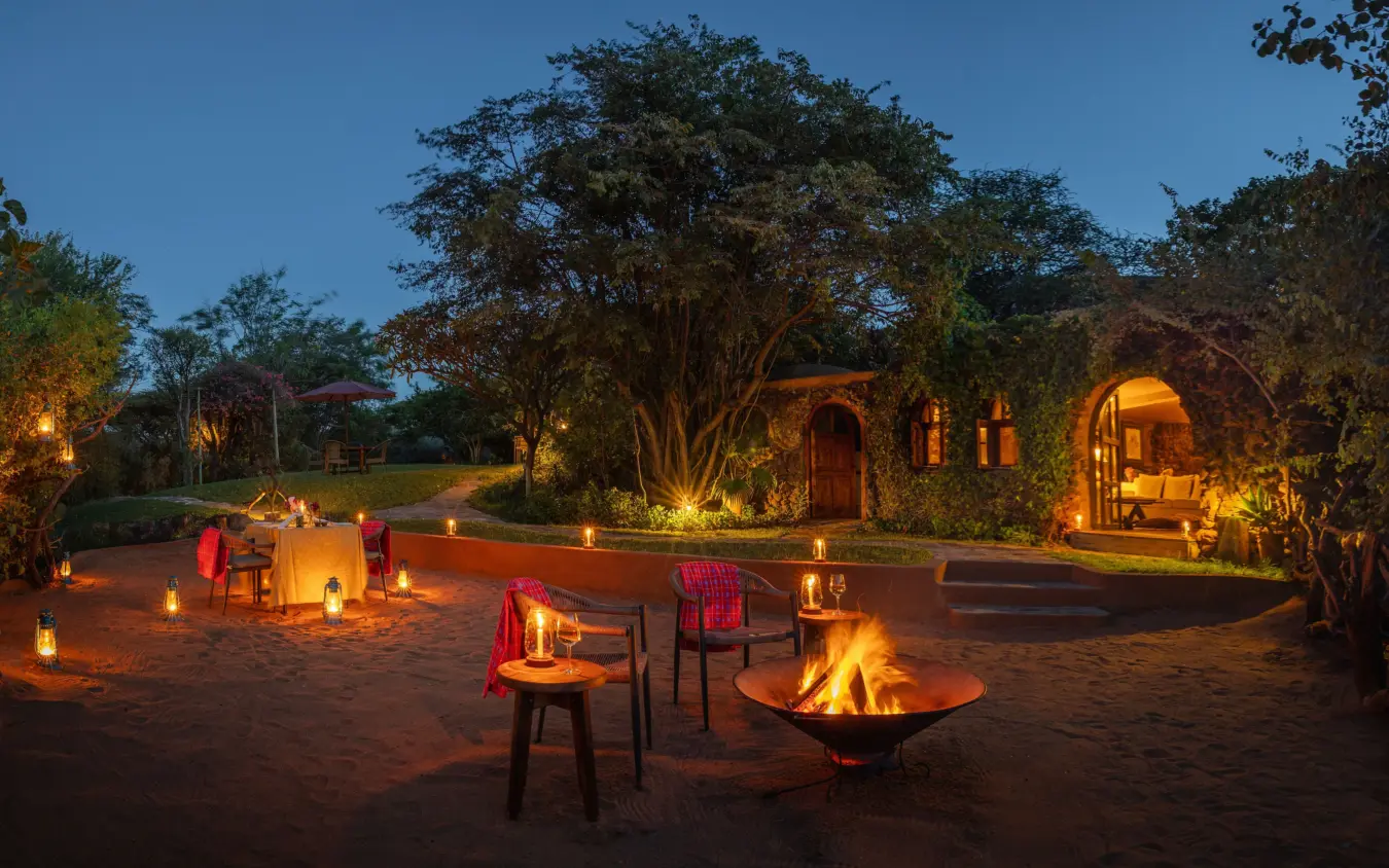 Evening campfire gathering with illuminated seating areas under trees, Lewa Wilderness, Laikipia Highlands, Kenya