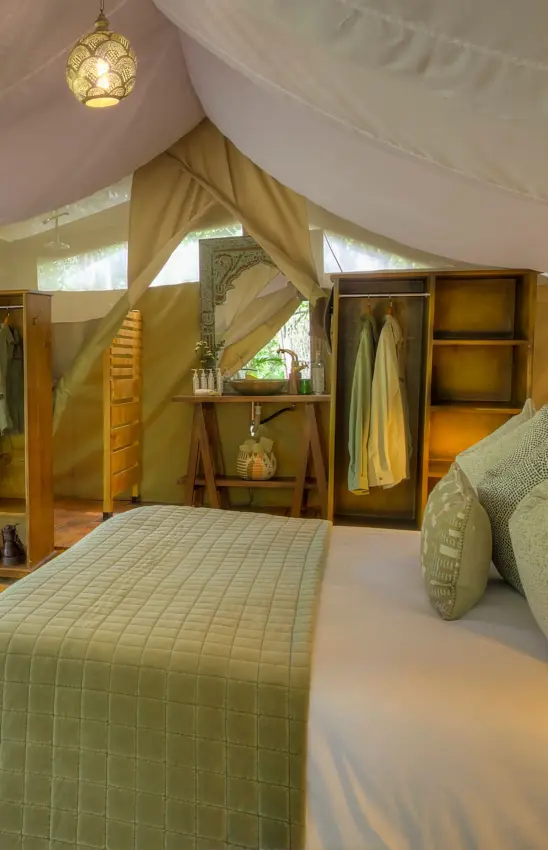 Luxury safari tent bedroom interior with canvas canopy and wooden furnishings, Naibor Camp, Maasai Mara, Kenya