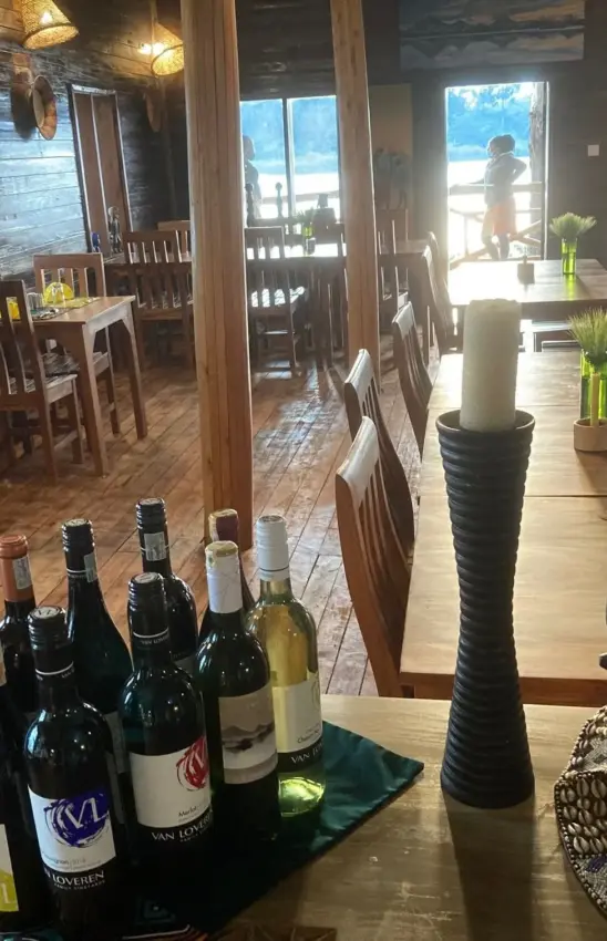 Restaurant interior with wine bottles and lake view beyond, Mutanda Lake Resort, Lake Mutanda, Uganda