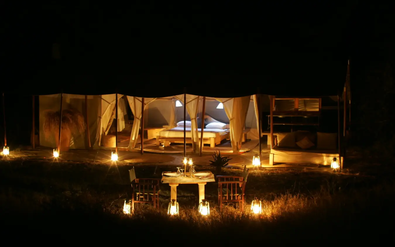 Illuminated luxury safari tent camp at night in savanna, Naibor Camp, Maasai Mara, Kenya