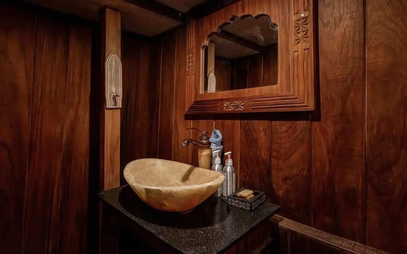 Luxury bathroom with stone vessel sink and wooden paneling, NaiSabah, Lamu Archipelago, Kenya