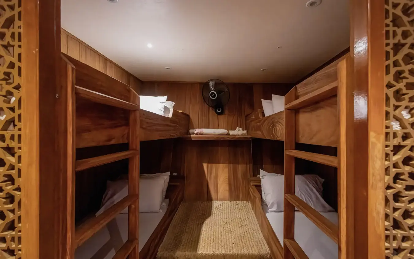 Wooden bunk room with four beds and decorative carved doorframes, NaiSabah, Lamu Archipelago, Kenya