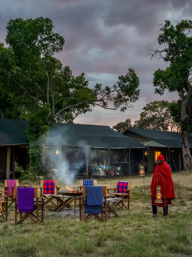 Campfire gathering at safari camp with colorful chairs at dusk, Ndutu Mobile Tented Camp, Serengeti National Park, Tanzania