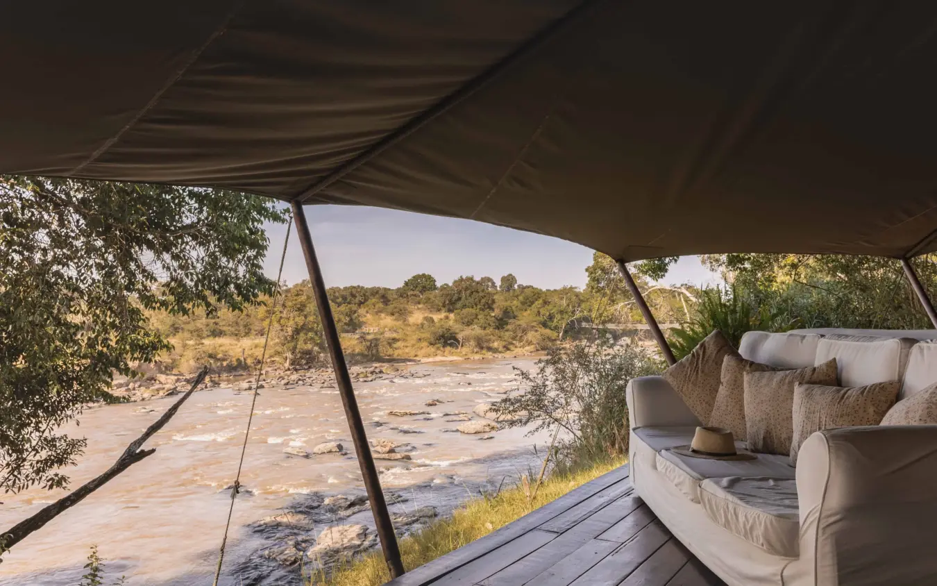 Luxury safari camp deck with lounge seating overlooking river, Ngare Serian, Maasai Mara, Kenya