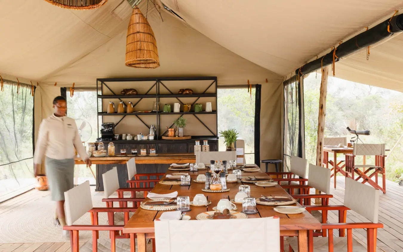 Canvas safari tent dining area with wooden furniture and open sides, Nkasa Linyanti, Zambezi Region, Namibia