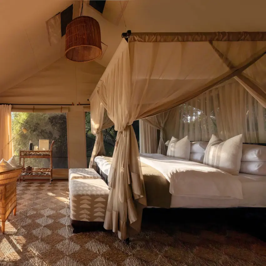 Luxury safari tent interior with four-poster bed and open-air deck overlooking landscape, Nkasa Linyanti, Zambezi Region, Namibia