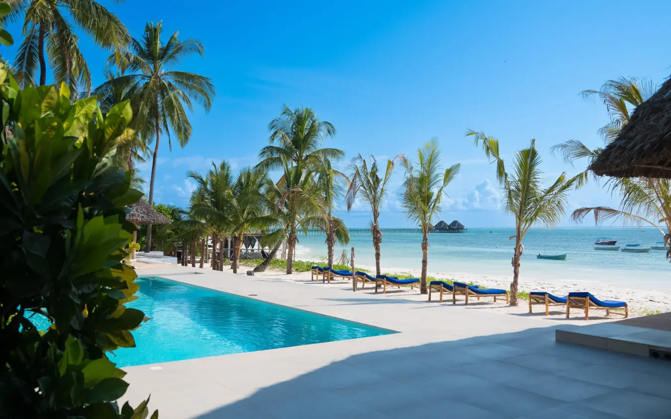 Resort pool and beach with palm trees and moored boats in tropical lagoon, Ocean Boutique Hotel, Zanzibar & Pemba, Tanzania