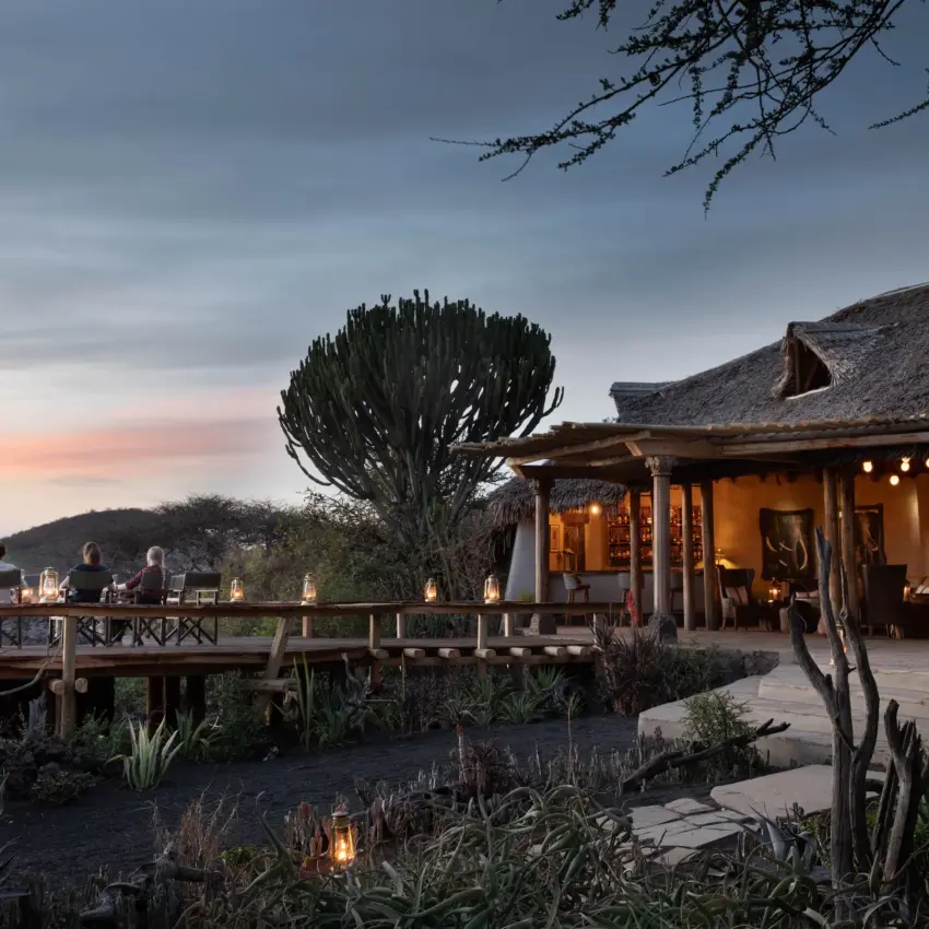 Luxury lodge with candlelit deck overlooking waterhole at dusk, Ol Donyo Lodge, Amboseli and Chyulu Hills, Kenya