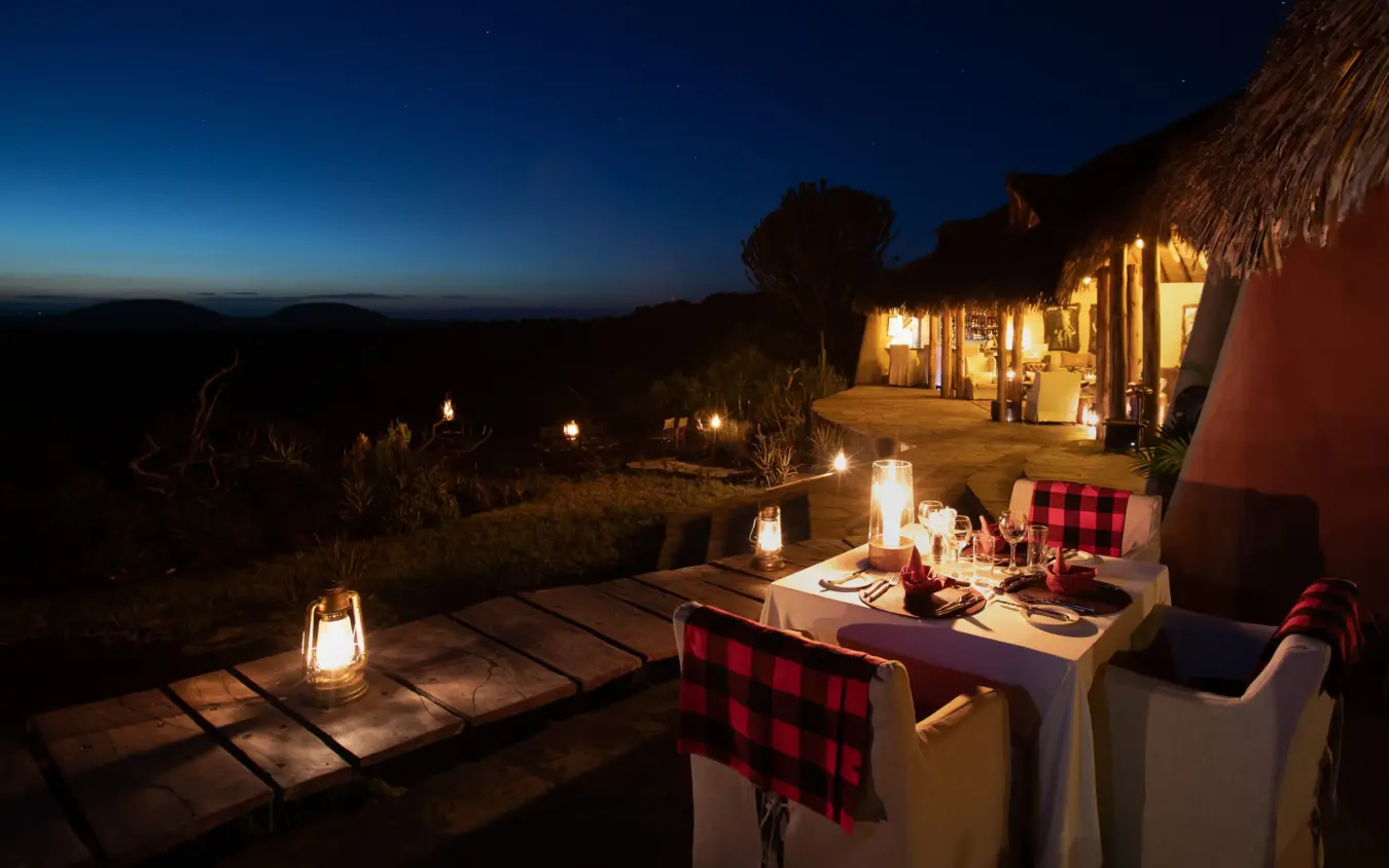 Outdoor dining table set for dinner under evening sky with lantern lighting, Ol Donyo Lodge, Amboseli and Chyulu Hills, Kenya
