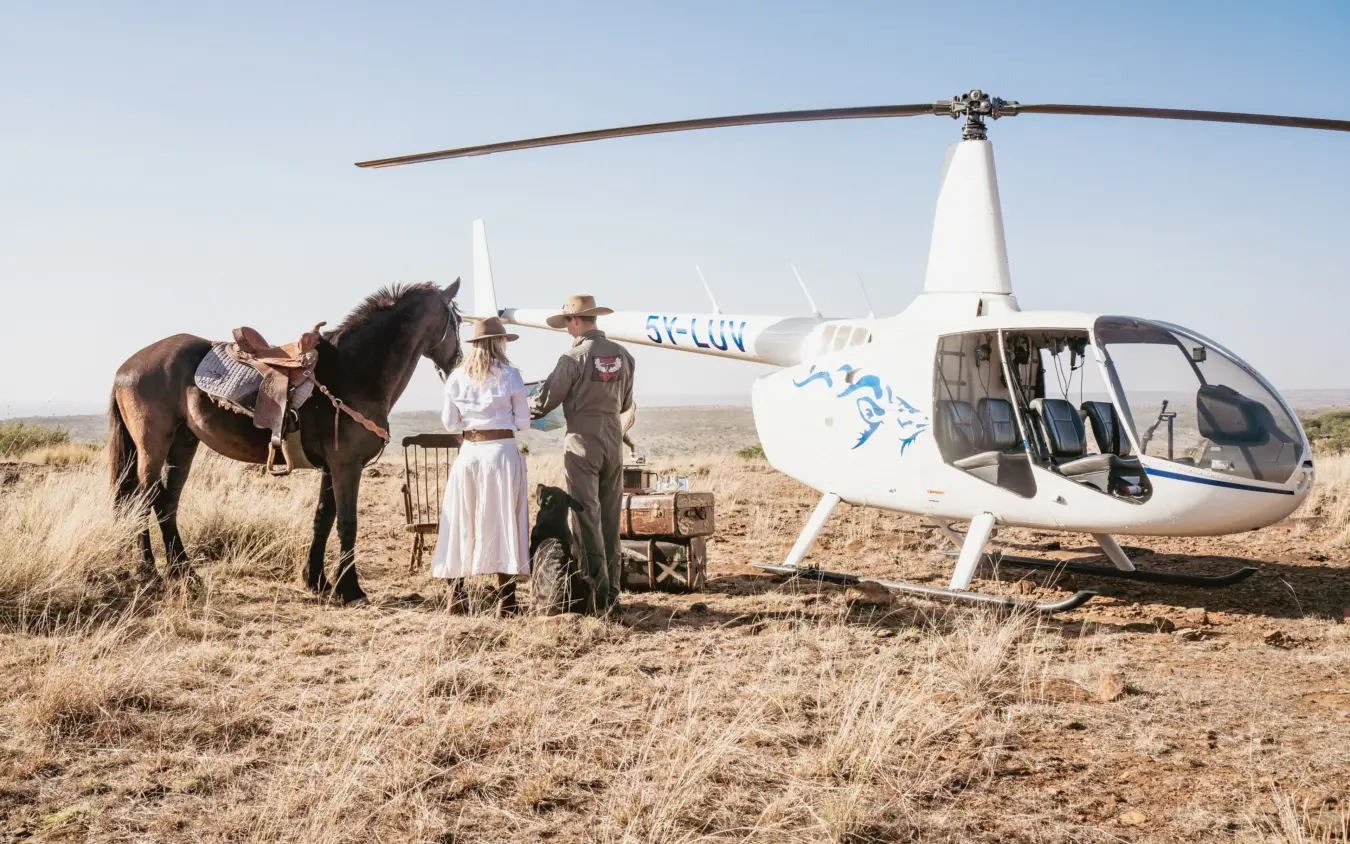 Helicopter landed on savanna with horse and guests in period dress, Ol Malo House, Laikipia Highlands, Kenya
