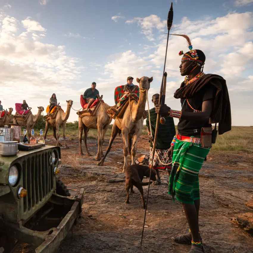Maasai warriors with camels meeting safari vehicle on dusty plains, Ol Malo House, Laikipia Highlands, Kenya