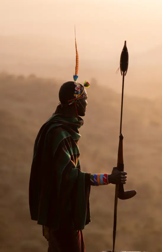 Maasai warrior holding spear in misty savanna landscape at dawn, Ol Malo House, Laikipia Highlands, Kenya