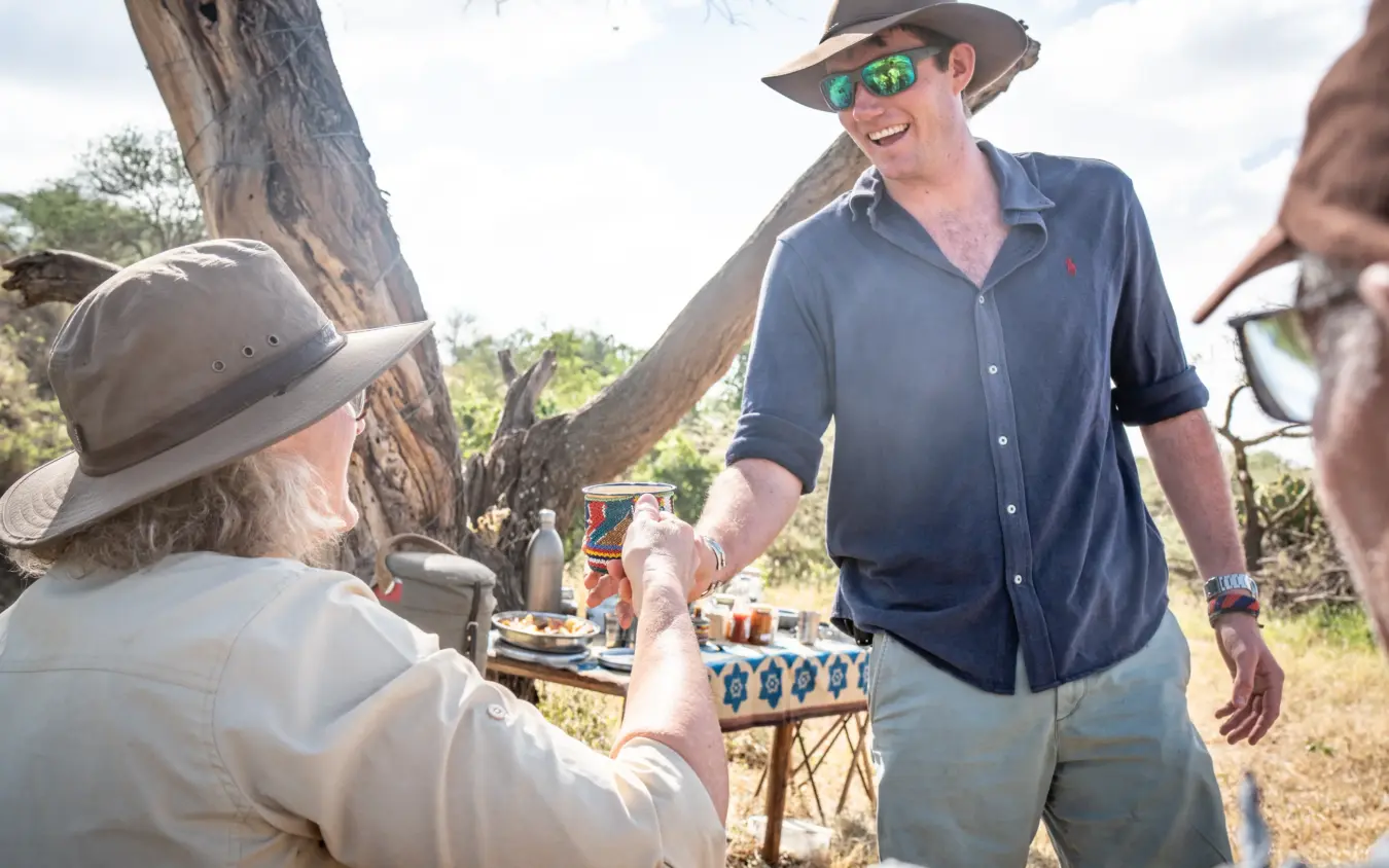 Guests dining outdoors under acacia tree on safari camp setup, Ol Malo House, Laikipia Highlands, Kenya