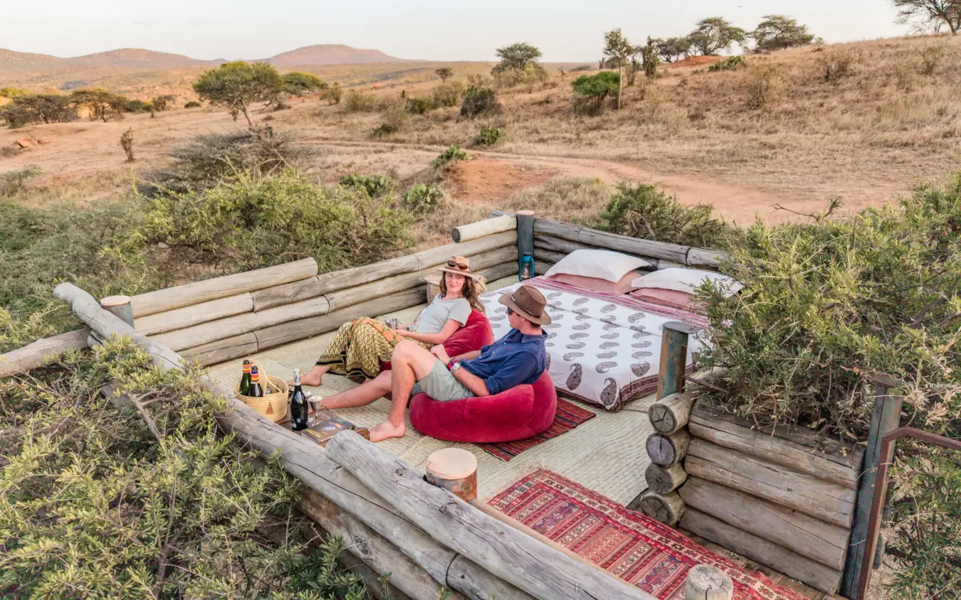 Guests relaxing in sunken outdoor bed overlooking arid savanna landscape, Ol Malo House, Laikipia Highlands, Kenya
