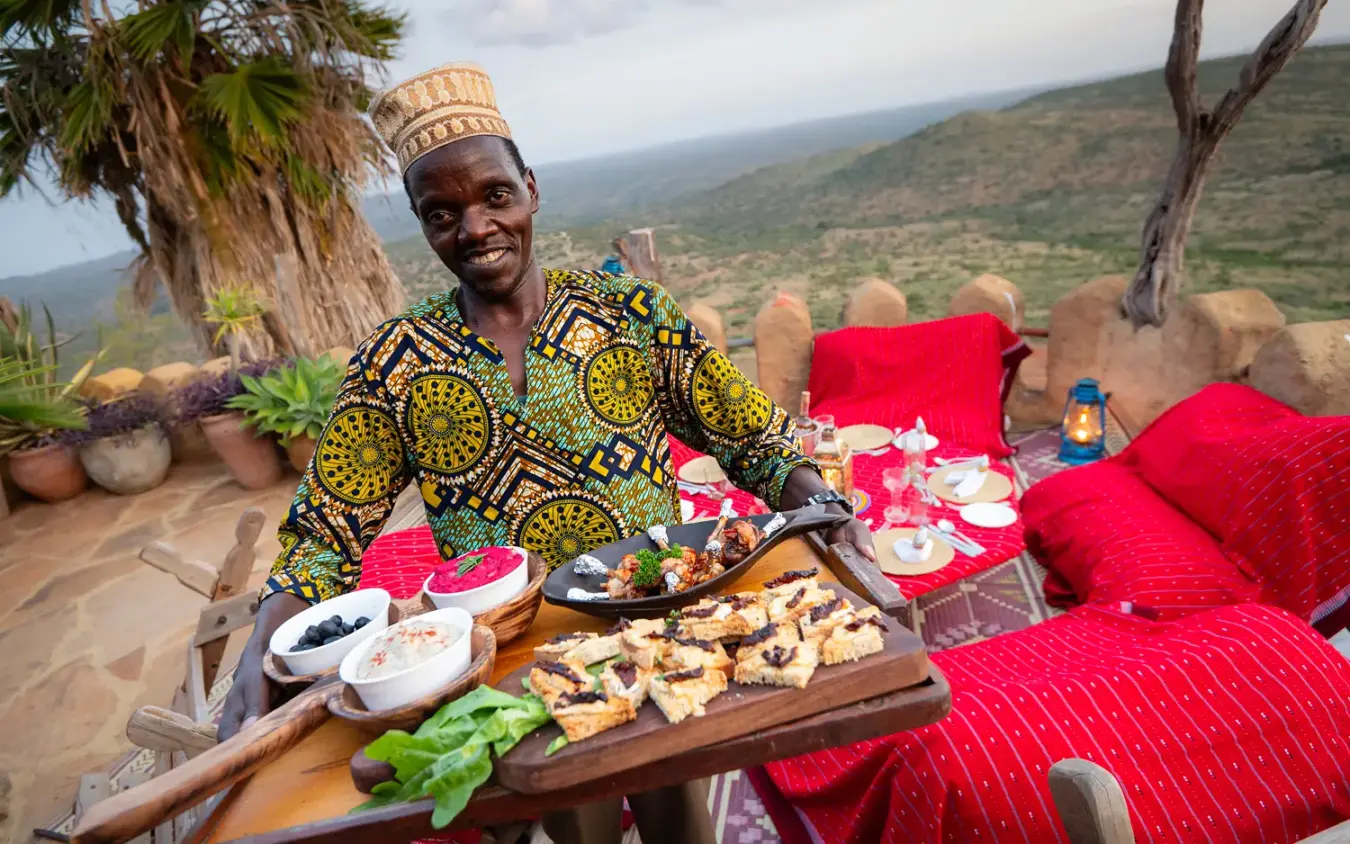 Chef presenting grilled food on terrace overlooking valley landscape, Ol Malo House, Laikipia Highlands, Kenya